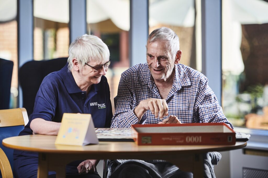 Companion care, carer and older gentleman enjoying a jigsaw together.